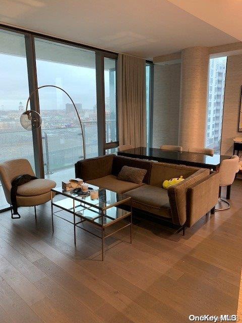 living room with wood-type flooring, a wall of windows, and a healthy amount of sunlight