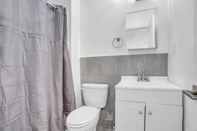 bathroom with a shower with curtain, vanity, tile walls, and toilet