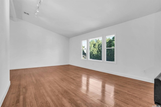 unfurnished room featuring light hardwood / wood-style floors, vaulted ceiling, and track lighting