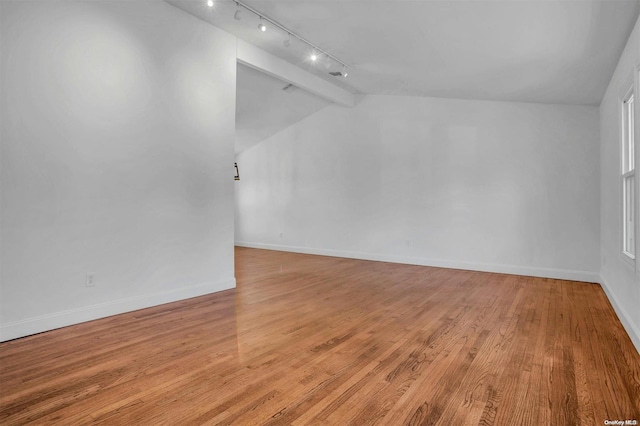 empty room featuring vaulted ceiling with beams and light hardwood / wood-style flooring