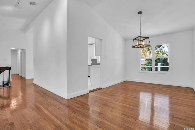 interior space with track lighting, high vaulted ceiling, a notable chandelier, and hardwood / wood-style flooring