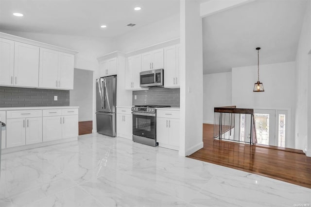 kitchen with hanging light fixtures, stainless steel appliances, backsplash, vaulted ceiling, and white cabinets