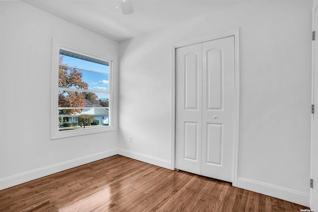 unfurnished bedroom with hardwood / wood-style flooring, ceiling fan, and a closet