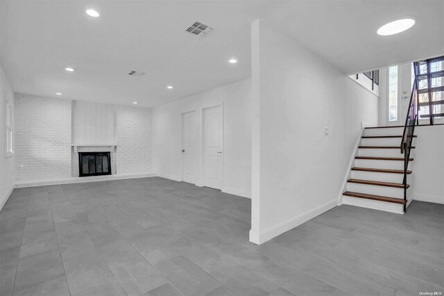 basement with brick wall and a brick fireplace