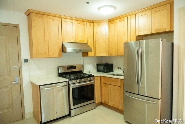 kitchen with light tile patterned floors, backsplash, stainless steel appliances, and sink