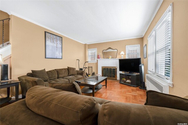 living room with radiator, a brick fireplace, crown molding, and parquet flooring