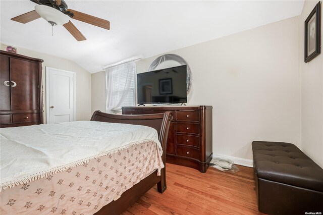 bedroom with ceiling fan, light wood-type flooring, and vaulted ceiling