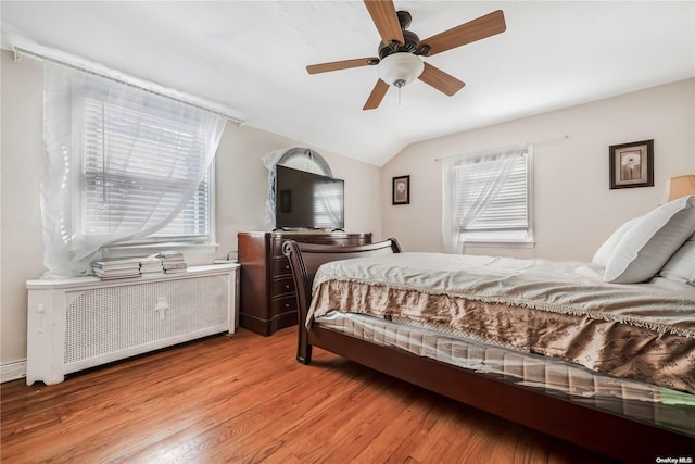 bedroom with radiator, ceiling fan, light hardwood / wood-style floors, and lofted ceiling
