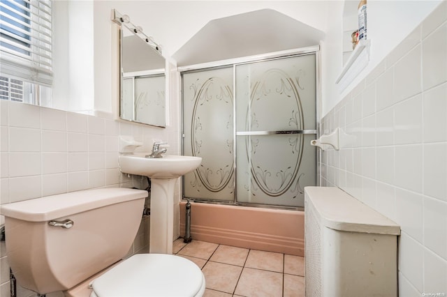 bathroom with toilet, tile patterned floors, tile walls, and enclosed tub / shower combo