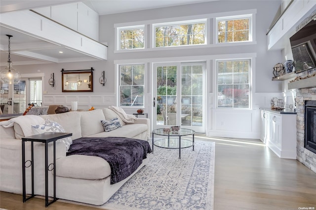 living room featuring a fireplace, hardwood / wood-style floors, beamed ceiling, and a healthy amount of sunlight