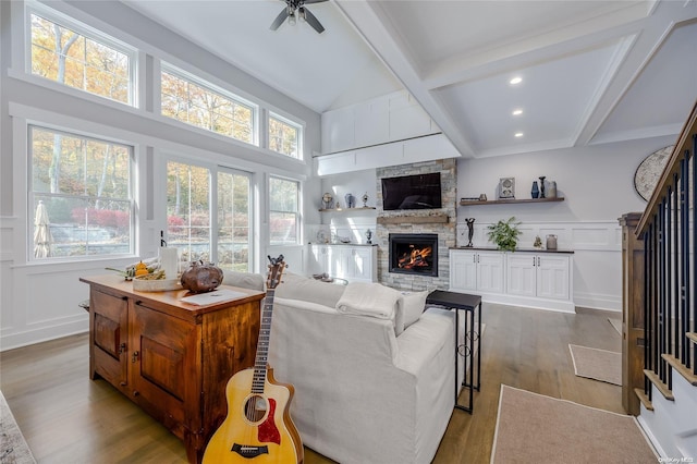 living room featuring beamed ceiling, ceiling fan, light hardwood / wood-style floors, and a fireplace