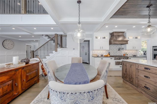 dining room featuring beam ceiling, light hardwood / wood-style floors, crown molding, and coffered ceiling