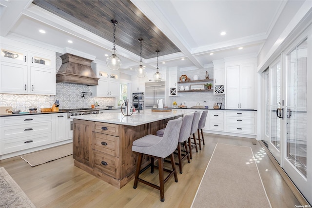 kitchen with white cabinets, custom range hood, decorative backsplash, and a spacious island