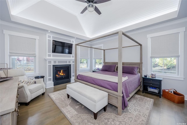 bedroom featuring multiple windows, hardwood / wood-style floors, ceiling fan, and crown molding