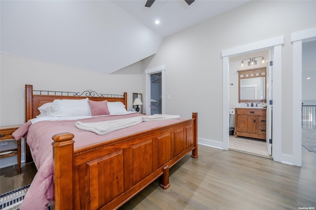 bedroom featuring light hardwood / wood-style flooring, ensuite bath, ceiling fan, and lofted ceiling