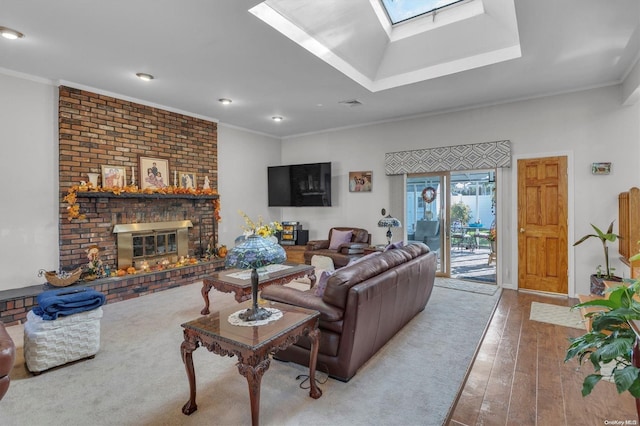 living room with a skylight, ornamental molding, light hardwood / wood-style floors, and a brick fireplace