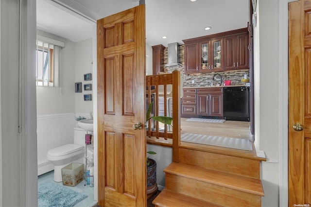 interior space featuring decorative backsplash, baseboard heating, sink, tile patterned flooring, and toilet