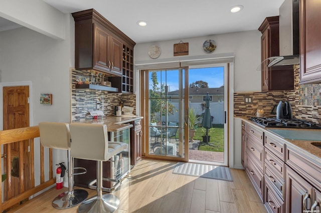 kitchen featuring light hardwood / wood-style floors, light stone countertops, black gas cooktop, and tasteful backsplash