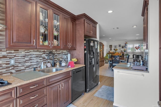 kitchen with black appliances, sink, decorative backsplash, light stone countertops, and light hardwood / wood-style floors