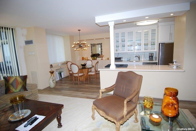 living room with sink, light wood-type flooring, and an inviting chandelier