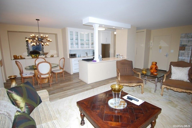 living room featuring a notable chandelier, light hardwood / wood-style floors, and decorative columns