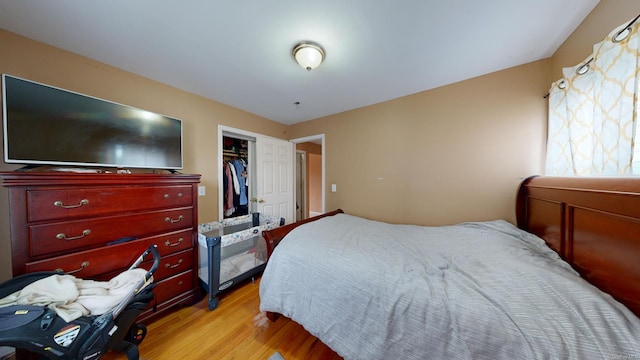 bedroom with a walk in closet, a closet, and light hardwood / wood-style flooring