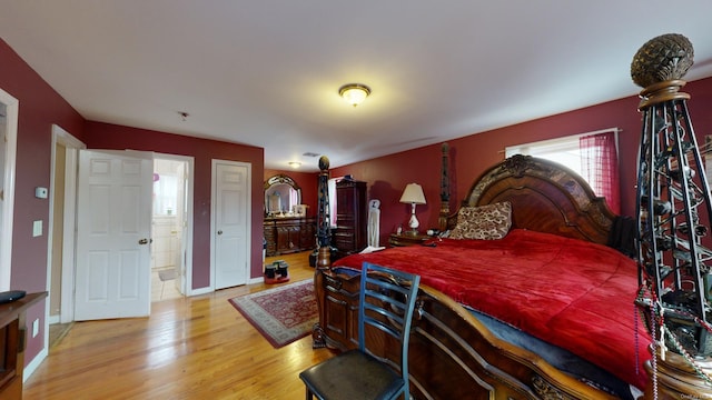 bedroom featuring connected bathroom and light hardwood / wood-style flooring