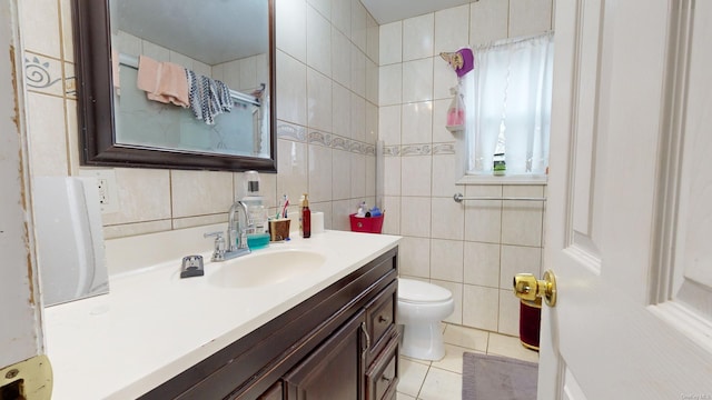 bathroom featuring toilet, vanity, tile patterned floors, and tile walls