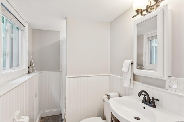 bathroom featuring a healthy amount of sunlight, toilet, and sink