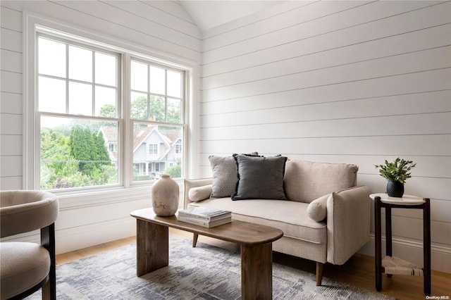 living area featuring hardwood / wood-style flooring, vaulted ceiling, and wood walls