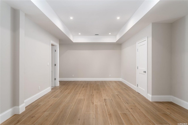 spare room with a raised ceiling and light wood-type flooring