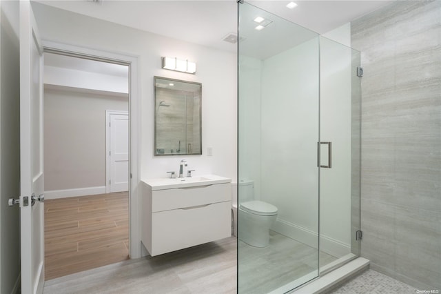 bathroom featuring hardwood / wood-style floors, vanity, a shower with door, and toilet