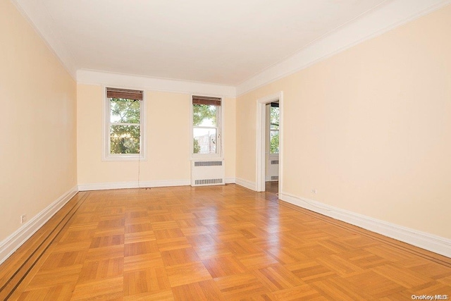 spare room with radiator, light parquet floors, and ornamental molding