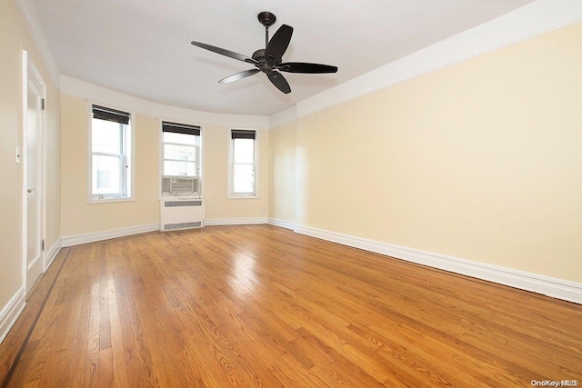 unfurnished room featuring cooling unit, crown molding, light hardwood / wood-style flooring, ceiling fan, and radiator heating unit