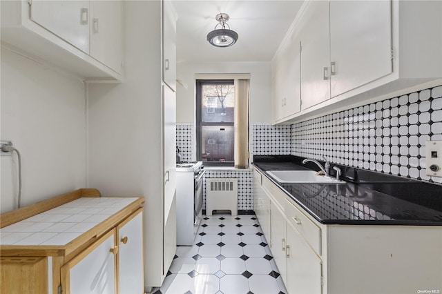 clothes washing area with washer and dryer, radiator heating unit, and sink