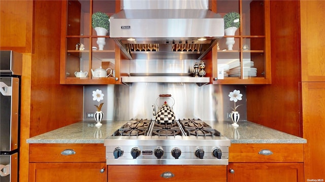 kitchen featuring appliances with stainless steel finishes, light stone counters, and wall chimney exhaust hood