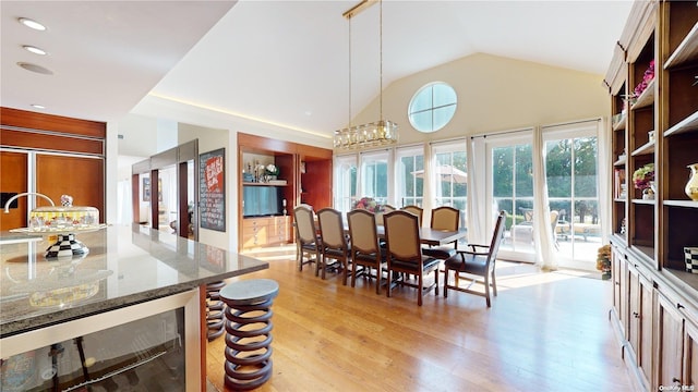 dining room featuring a chandelier, beverage cooler, lofted ceiling, and light hardwood / wood-style floors