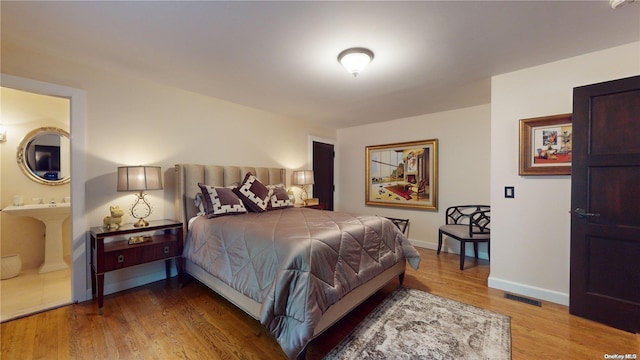 bedroom featuring hardwood / wood-style flooring and connected bathroom