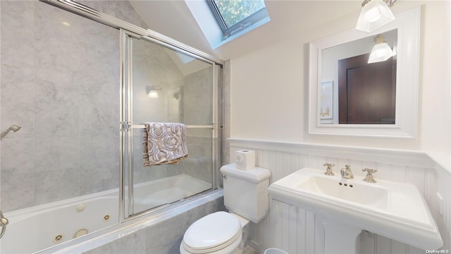 full bathroom featuring lofted ceiling with skylight, sink, combined bath / shower with glass door, and toilet