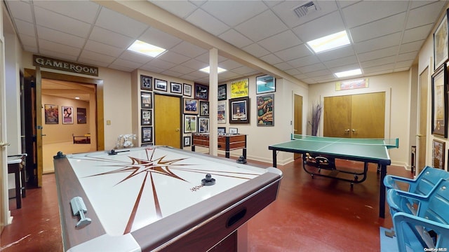 recreation room featuring a drop ceiling and concrete flooring