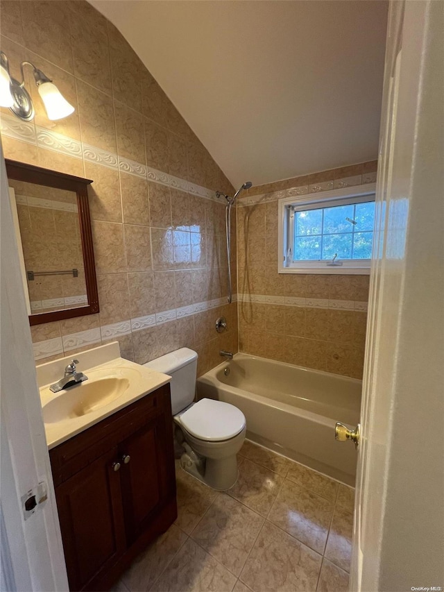 full bathroom featuring vanity, lofted ceiling, tiled shower / bath, toilet, and tile walls