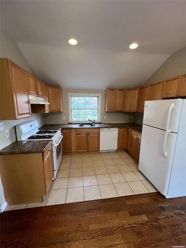 kitchen featuring lofted ceiling, white appliances, dark stone counters, sink, and light hardwood / wood-style flooring