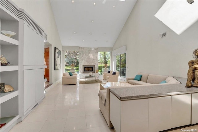 tiled living room with built in shelves, a premium fireplace, and high vaulted ceiling