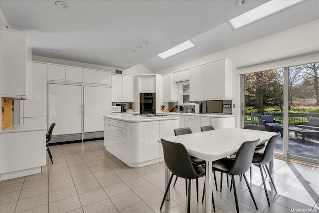 kitchen featuring stainless steel gas stovetop, decorative backsplash, paneled built in refrigerator, a kitchen island, and white cabinetry