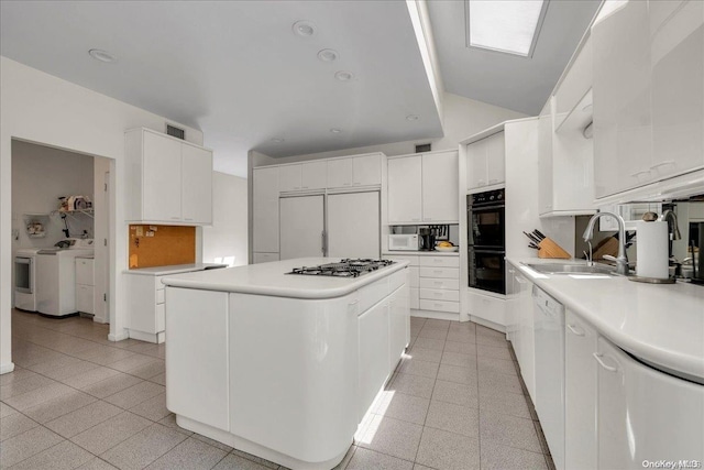 kitchen with a center island, white cabinetry, sink, and washing machine and clothes dryer