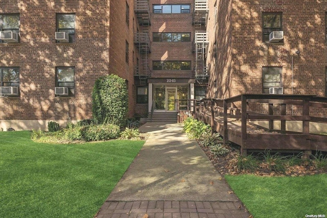 property entrance featuring cooling unit, a yard, and a wooden deck