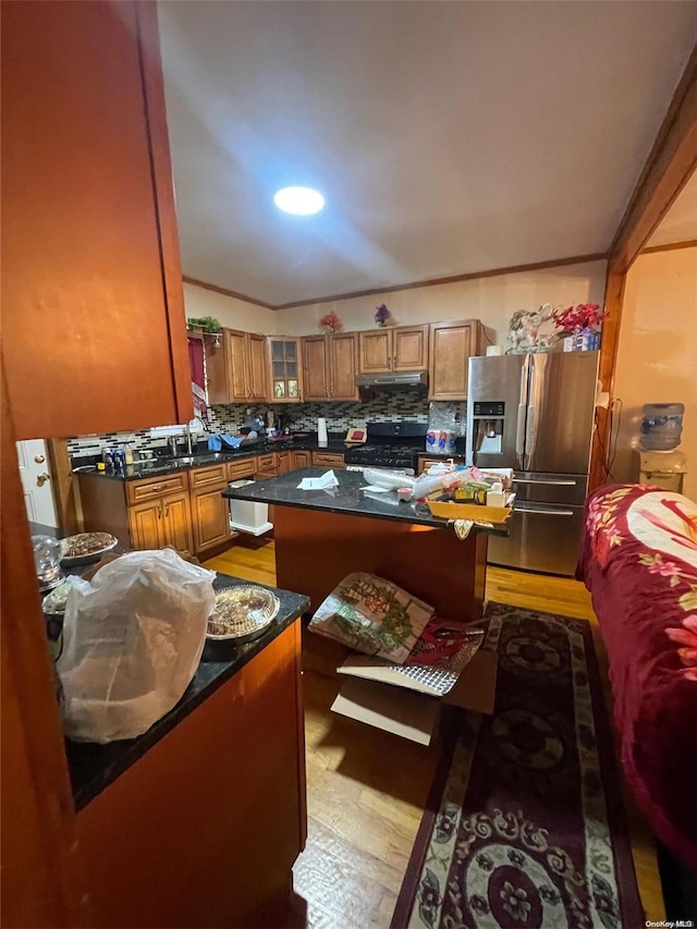 kitchen featuring backsplash, stainless steel refrigerator with ice dispenser, light hardwood / wood-style floors, a kitchen island, and black range with gas cooktop