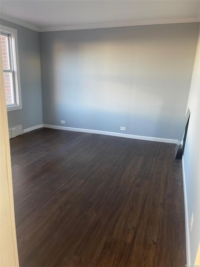 empty room with dark hardwood / wood-style flooring, ornamental molding, and a baseboard heating unit