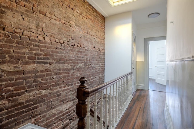 corridor with brick wall and dark wood-type flooring