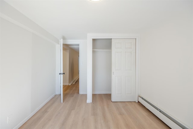 unfurnished bedroom with light hardwood / wood-style flooring and a baseboard radiator